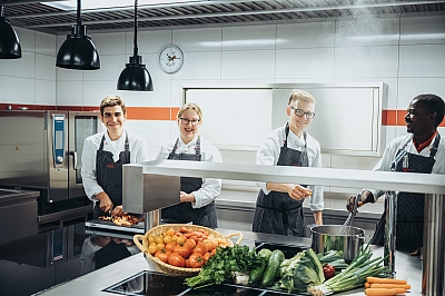 LBS-Küchenkräfte-kochen-gemeinsam-mit-frischem-Gemüse Küchenkräfte stehen in der Küche der LBS NordWest und kochen mit frischen Zutaten