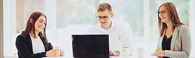 Auszubildende-der-LBS-arbeiten-gemeinsam-am-Laptop LBS Azubis stehen zu dritt am Stehtisch und schauen gemeinsam auf einen Laptop.