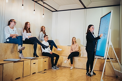LBS-Auszubildende-hu00e4lt-vor-anderen-Azubis-eine-Pru00e4sentation-am-Smartboard LBS Auszubildende sitzen zusammen und schauen gemeinsam auf ein Smartboard, welches von einer Auszubildenden beschriftet wird.
