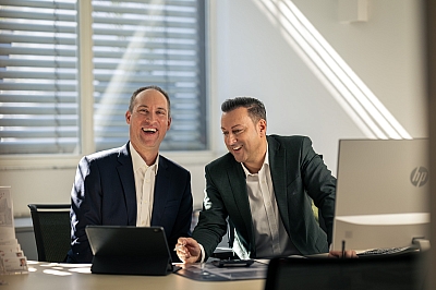Zwei-LBS-Berater-sitzen-lachend-nebeneinander-im-Büro Zwei LBS-Berater sitzen lachend nebeneinander im Büro.