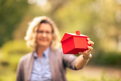 LBS-Beraterin-hält-Haus-Modell-hoch-und-lächelt-in-die-Kamera LBS-Beraterin hält LBS Haus-Modell hoch und lächelt in die Kamera.